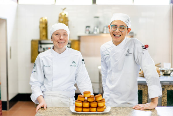 Alumnos de la carrera en artes culinarias sonriendo en clase.